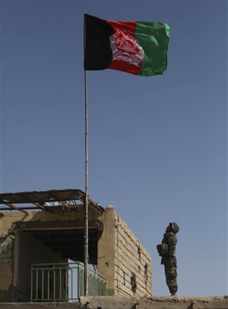 An Afghan Army soldier salutes an Afghan flag after hoisting it on a building in a market in Marjah, Afghanistan, Wednesday, Feb. 17, 2010 (AP Photo/Altaf Qadri)